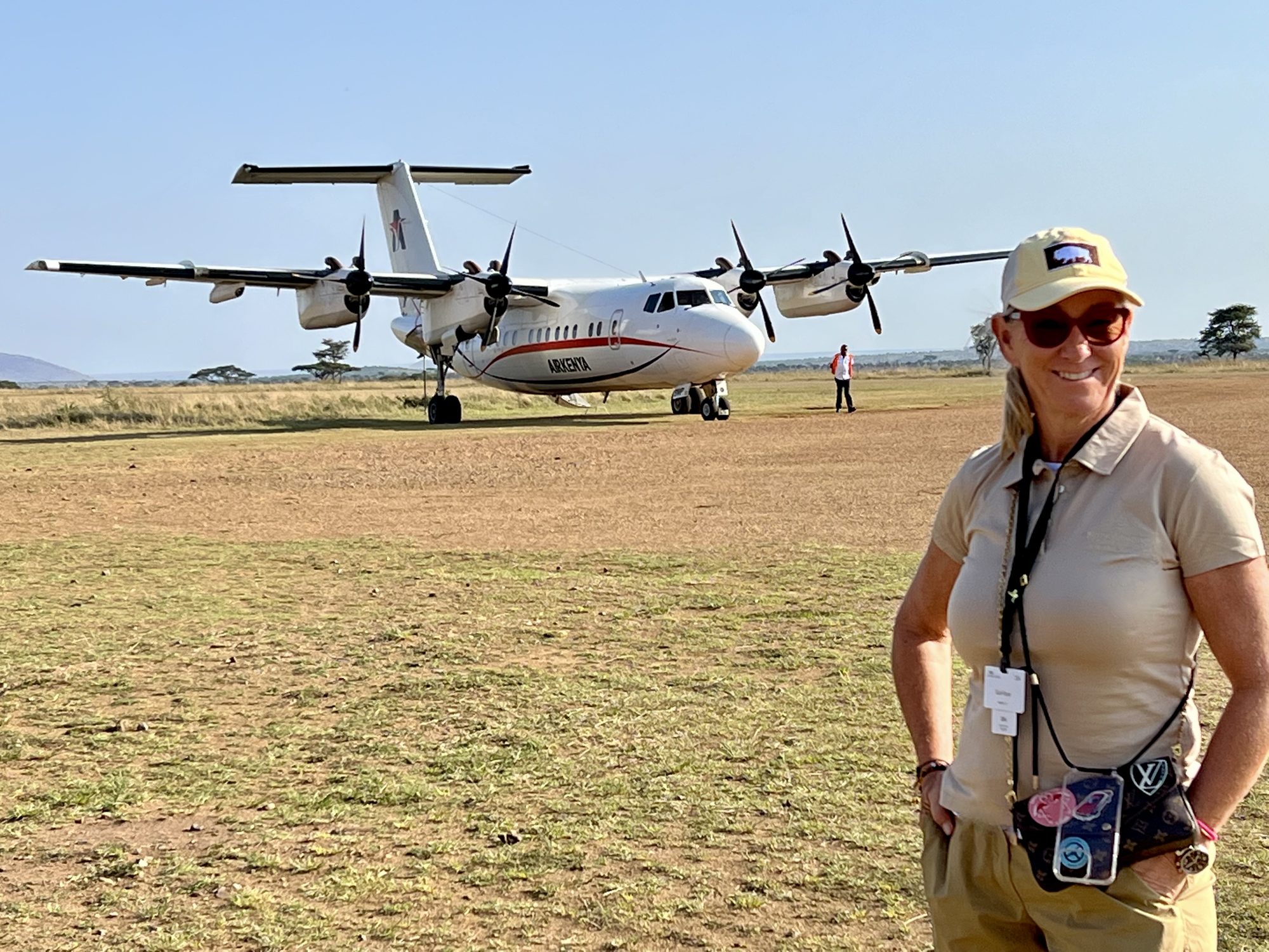 Susi on a grass airstrip in the Serengeti in front of a safari bush plane