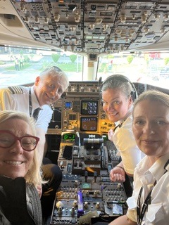 Susi taking a selfie with the flight crew in an airliner cockpit