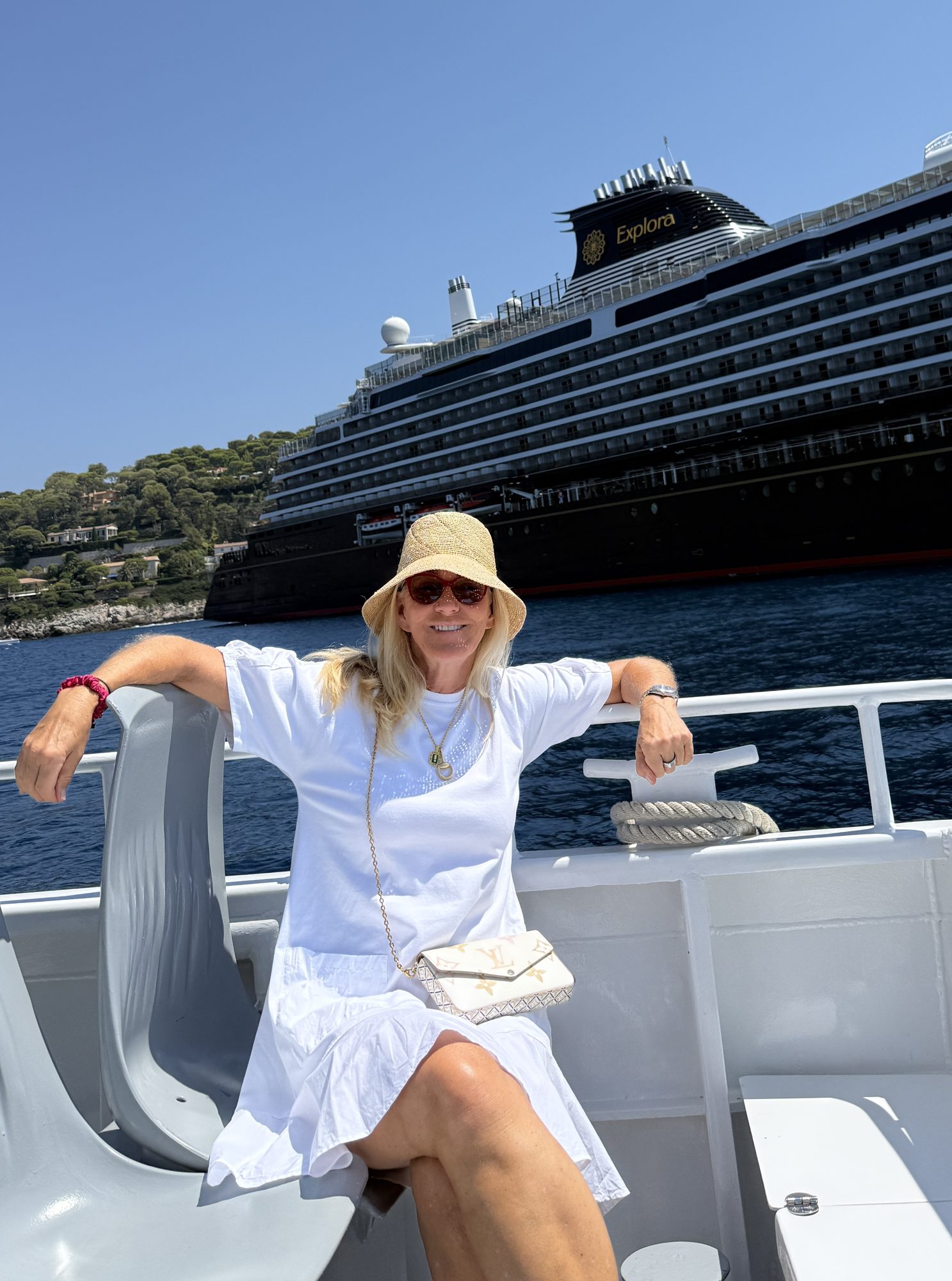 Susi Rose on a tender boat with an Explora Journeys ship anchored behind her