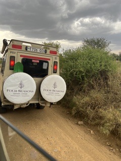 A Four Seasons safari vehicle on a dirt track through the bush