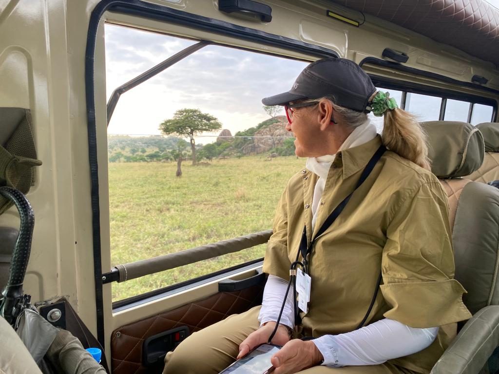 Susi looking out from a safari vehicle across the savanna