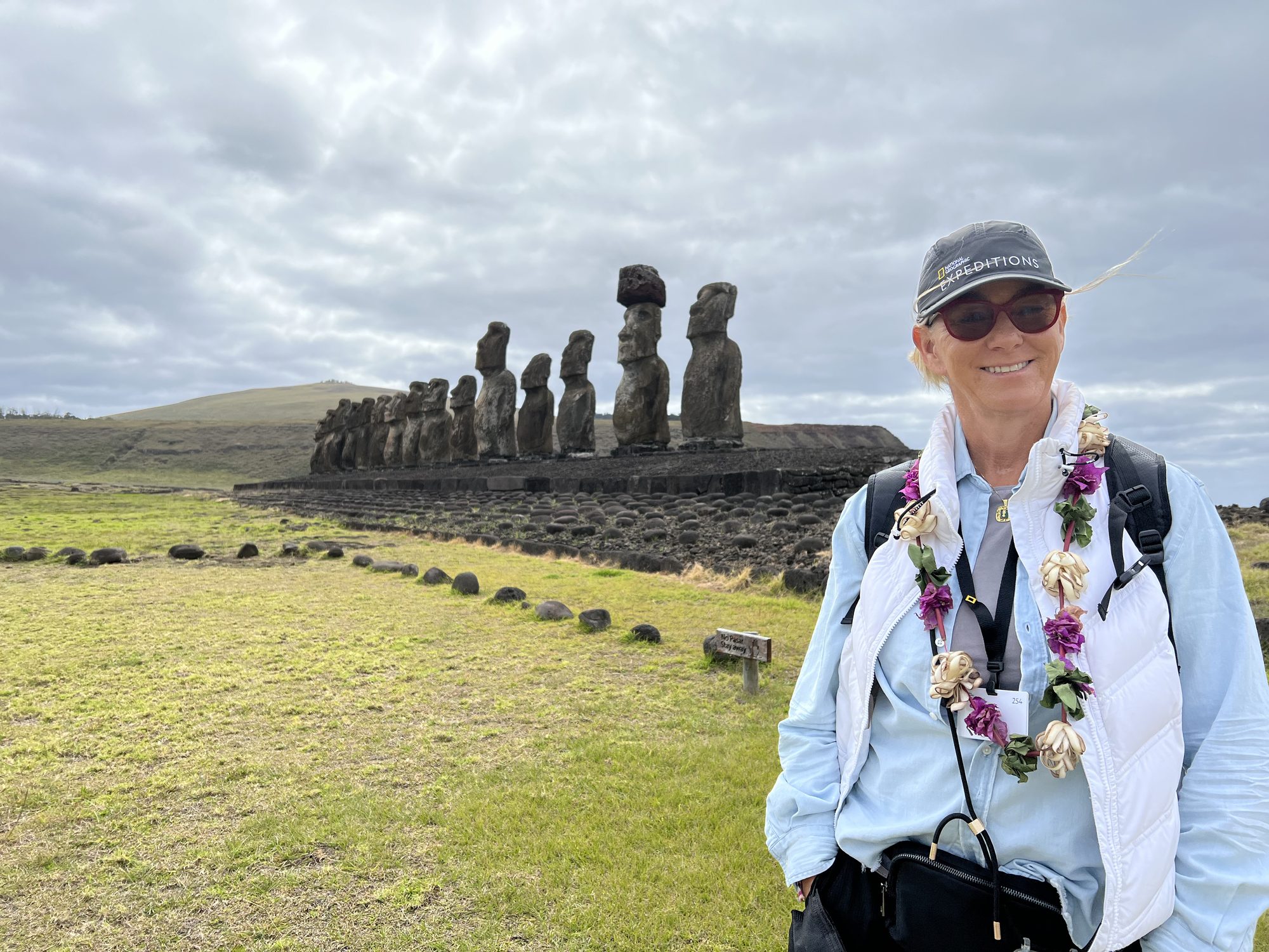 Susi wearing a flower lei in front of the fifteen moai of Ahu Tongariki on Easter Island